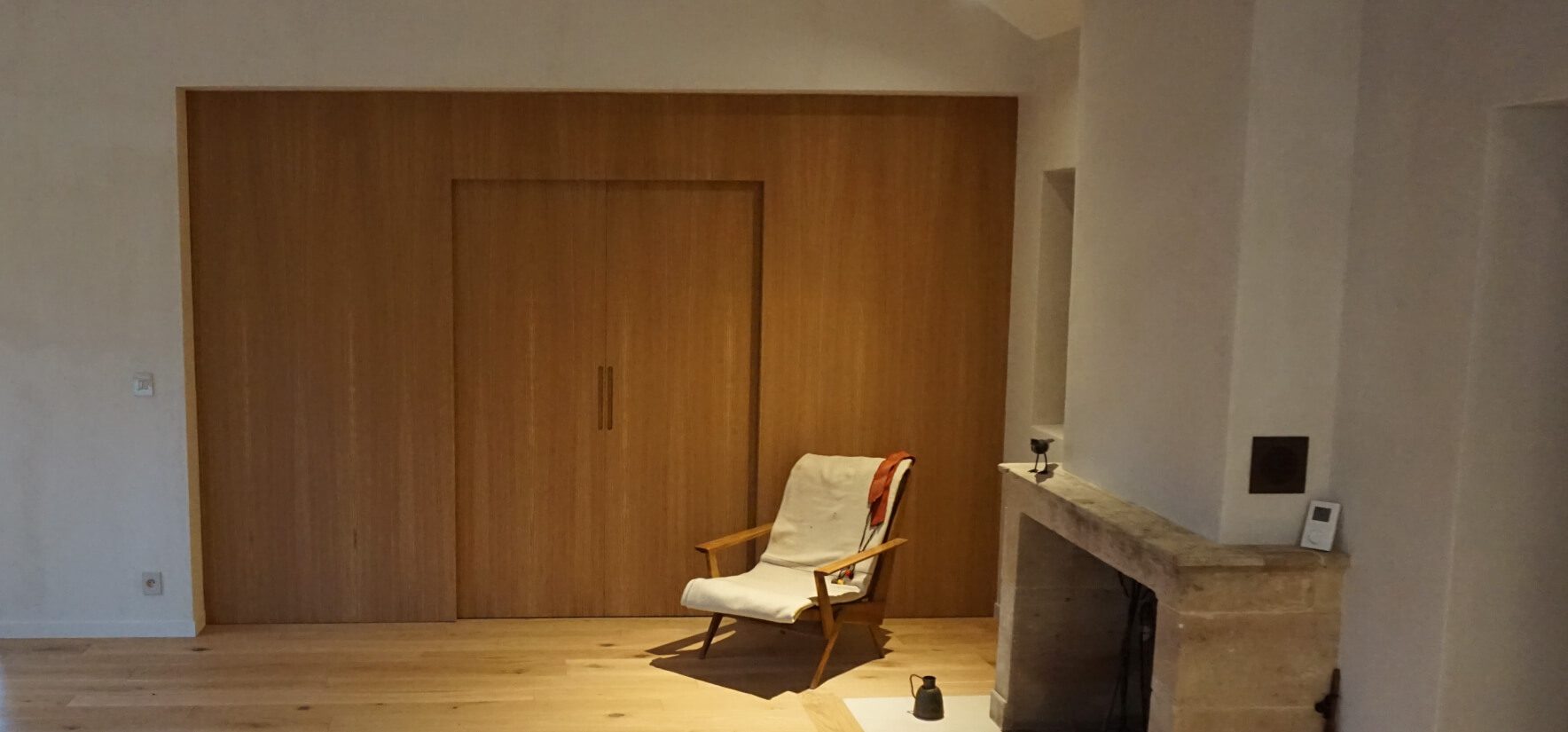 Painel divisório em MDF de 19 mm folheado a carvalho natural fechado na sala de estar com poltrona