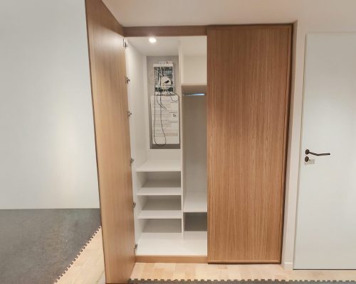 Interior de armário em laminado branco com prateleiras amovíveis e quadro elétrico.