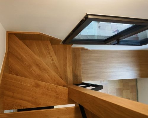 Escada de acesso ao piso superior em carvalho natural com guarda-corpos em ferro