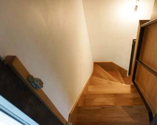 Escada de acesso ao piso superior em carvalho natural com guarda-corpos em ferro