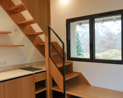 Vista lateral da mini cozinha em carvalho com prateleiras suspensas e LED