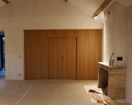 Painel de madeira de carvalho natural integrado em sala de estar ampla com lareira em pedra
