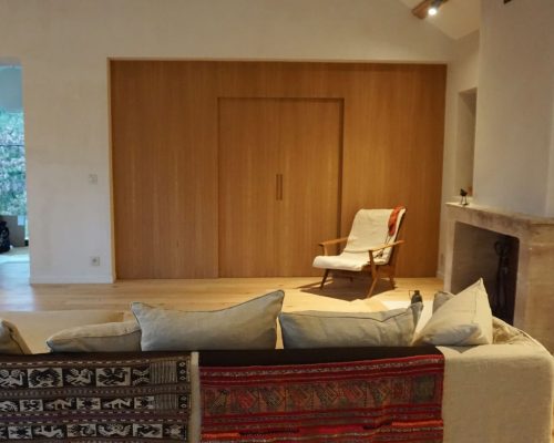 Sala de estar decorada com sofá moderno e painel de revestimento divisório em carvalho ao fundo