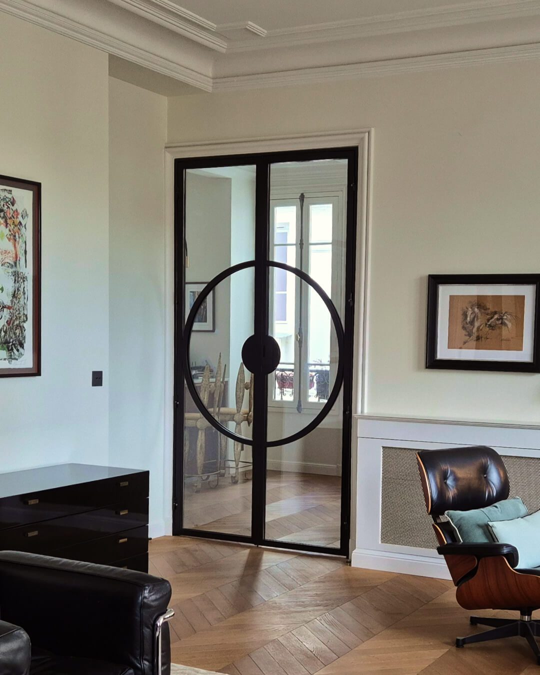 Porta dupla em ferro preto e vidro com design circular enquadrada no salão em Paris