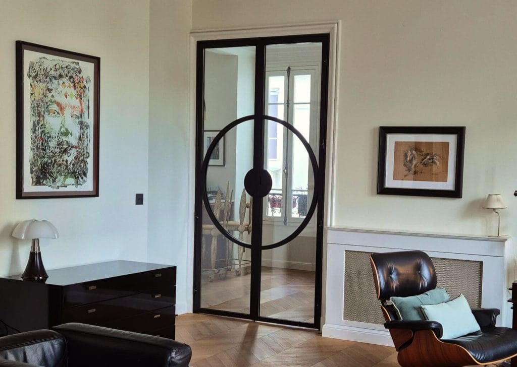 Porta dupla em ferro preto e vidro com design circular enquadrada no salão em Paris